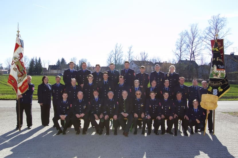 Die Mannschaft der Feuerwehr Eicherloh in Ausgehuniform, links die Vereinsfahne, rechts die Fahne mit dem Schriftzug Eicherloh